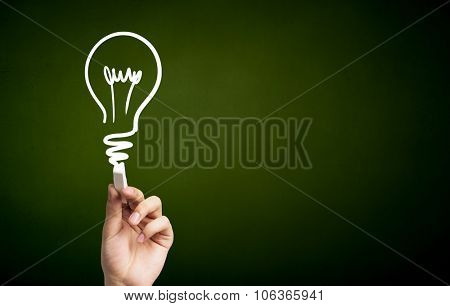 Human hand darwing light bulb as idea concept with chalk