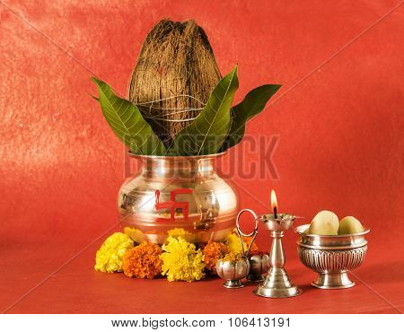 copper kalash with coconut and mango leaf with floral decoration, diya, haldi kumkum and sweet pedha