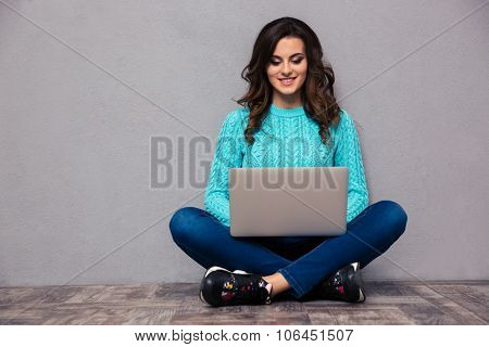 Portrait of a happy woman using laptop computer on the floor 