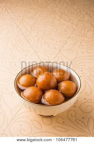 Gulab Jamun served in a round ceramic bowl - An Indian sweet dish, round shaped, black or brown text