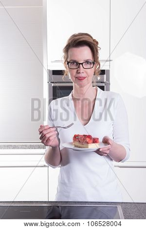 Attractive Woman In Modern Ktchen Eating Strawberry Cake