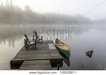 Green Canoe And Dock On A Misty Morning