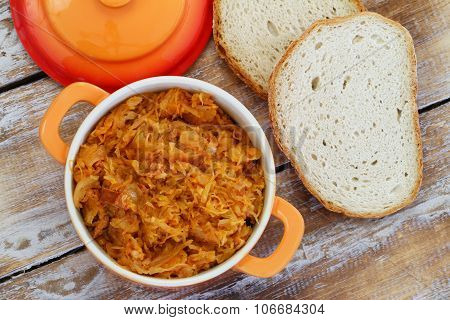 Traditional Polish bigos in saucepen and slices of freshly baked rustic bread