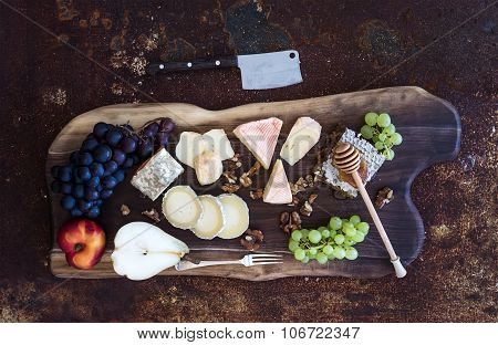 Wine appetizers set: French cheese selection, honeycomb, grapes, peach and walnuts on rustic wooden
