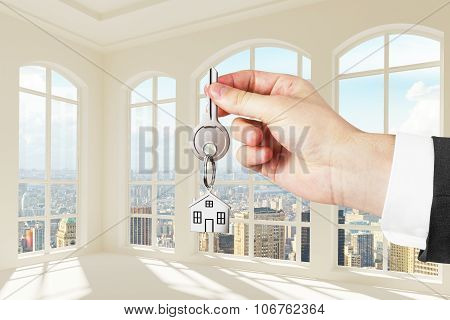 Man With Key In Hand In Modern Sunny White Room With City View