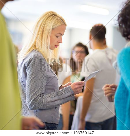 Young blond caucsian woman waiting in line.