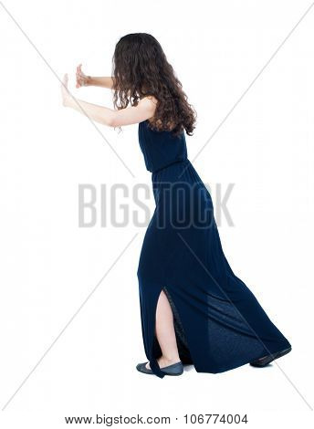 back view of woman pushes wall. Isolated over white background. Rear view people collection. backside view of person.  Girl in a blue evening dress is pushing the right wall.
