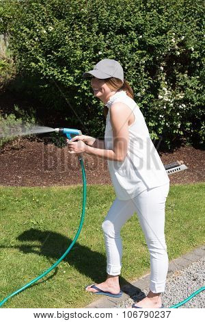 Attractive Young Woman Watering The Plants In The Garden