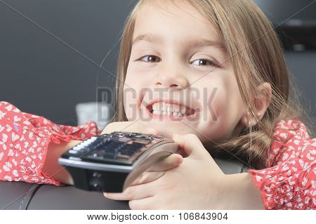 cute little girl with remote control in front of TV.