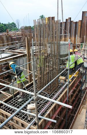 Construction Workers Using Concrete Vibrator to compact the concrete slurry
