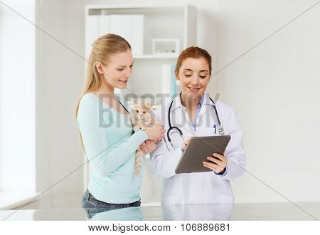 medicine, pet, health care, technology and people concept - happy woman and veterinarian doctor with tablet pc computer checking scottish fold kitten up at vet clinic