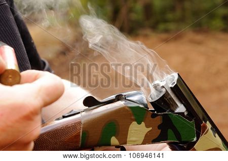 Smoking gun concept,  a double barreled over/under shotgun immediately after firing with shallow depth of field focused on the smoke leaving the breech