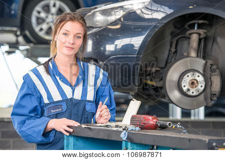 Female mechanic checking a car during a periodic technical service or MOT test,