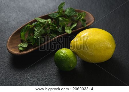 Close-up of mint leaf and sweet limes on black background