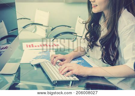 Closeup hand young asian business woman pressing the keyboard of computer for working in the modern Office over the photo blurred of teamwork backgroundpeople business concept