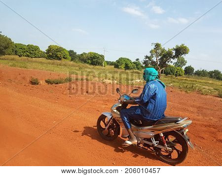 BAMAKO MALI - DEC 19 2016: African paysage with Touareg on his KTM bike driving fast ont the red african soil