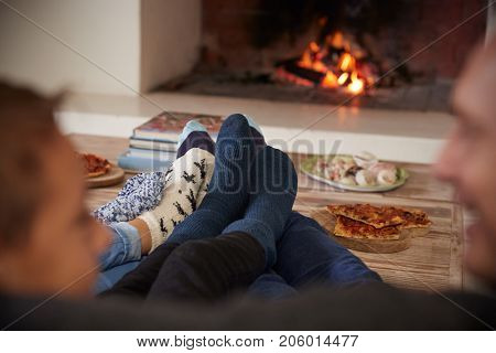 Close Up Of Feet As Family Relax Next To Open Fire