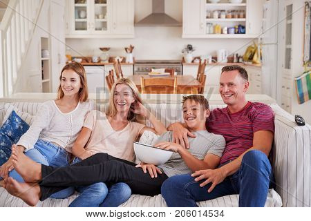 Family With Teenage Children Sitting On Sofa Watching TV Together