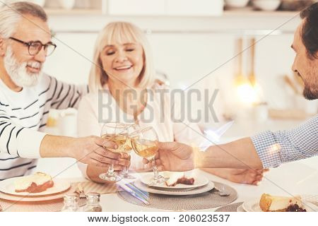 For you. Cheerful delighted family drinking wine and sitting at the table while enjoying celebration