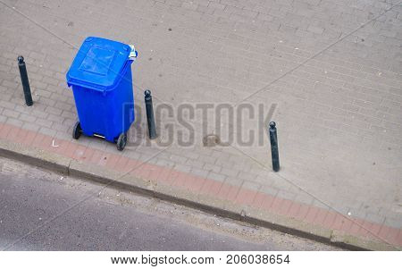 Cleanliness in city objects concept. Minimalist photo of blue trash can on street pavement