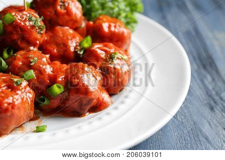 Plate with delicious meatballs on wooden table