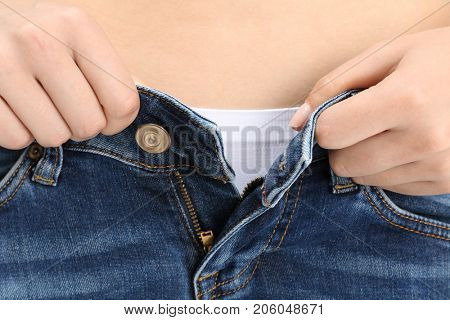 Young woman in undersized jeans, closeup. Diet concept