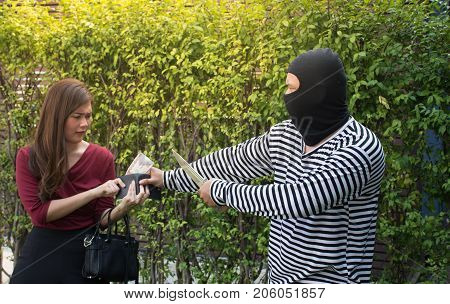 Male robber robbing a wallet threatening with knife to scared Asian woman,criminal concept