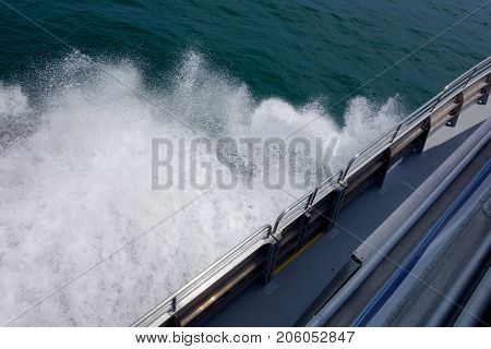 Speeding cruise ship cutting and splashing sea water underneath its deck into a salty cloud of white drops