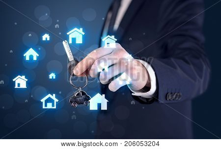 Businessman in suit holding keys with house graphics around and dark background