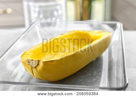 Baking dish with half of baked spaghetti squash on table