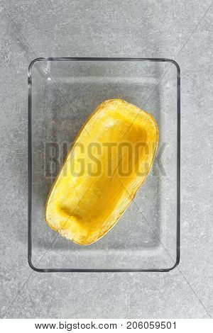 Baking dish with half of baked spaghetti squash on table