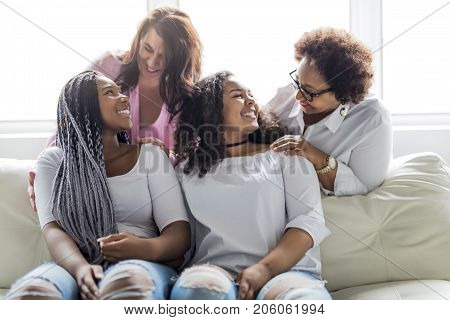 Two family Friends Sitting On Sofa Together having fun