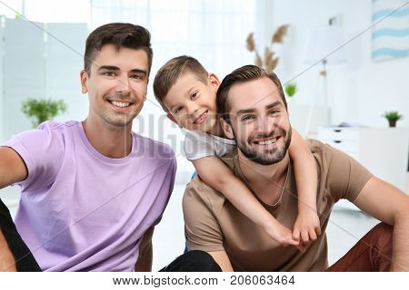 Happy male gay couple with foster son at home. Adoption concept