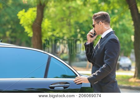 Handsome bodyguard near car outdoors