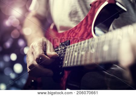 A rock lead guitarist playing electric guitar in action on stage