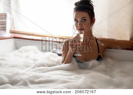 Pretty brunette in bicini with a glass of champagne in jacuzzi