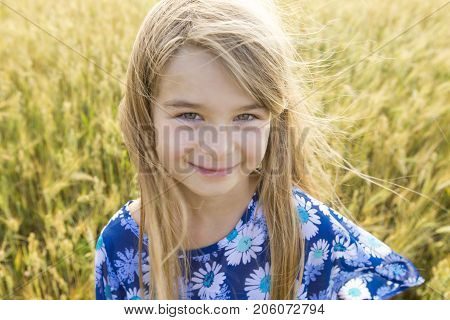 An Adorable little girl playing in the wheat field on a warm summer day