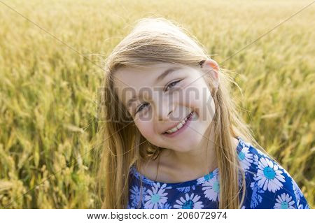 An Adorable little girl playing in the wheat field on a warm summer day