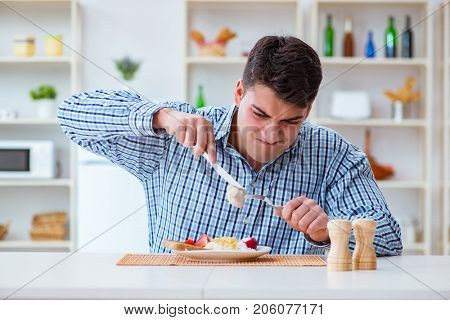 Man eating tasteless food at home for lunch