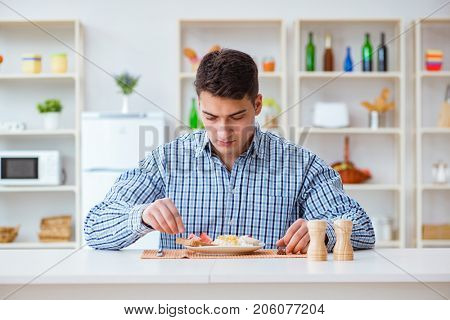 Young husband eating tasteless food at home for lunch