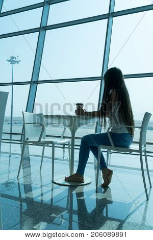 Girl Is Holding A Glass Of Coffee In Airport's Business Lounge With Aircraft