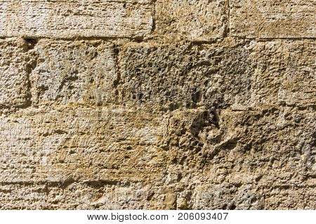 Horizontal photo with texture of typical wall in Tuscany Italy. The used stone is volcanic yellow tuf with holes and groves.