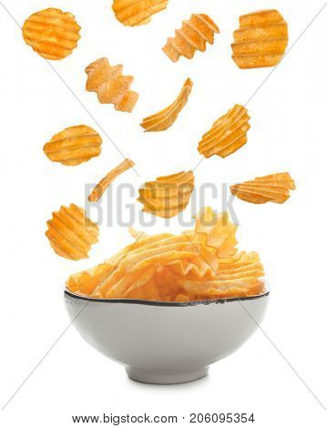 Tasty potato chips falling into bowl on white background