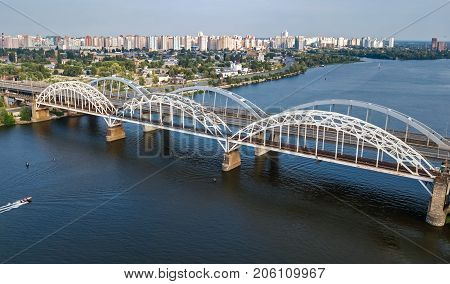 Aerial top view of automobile and railroad Darnitsky bridge across Dnieper river from above, Kiev (Kyiv) city skyline, Ukraine