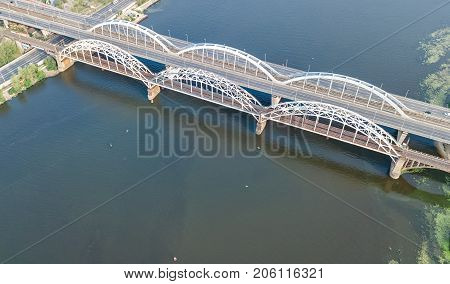 Aerial top view of automobile and railroad Darnitsky bridge across Dnieper river from above, Kiev (Kyiv) city skyline, Ukraine