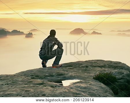 Tourist Sit On Peak Of Sandstone Rock And Watching Into Colorful Mist And Fog In  Morning Valley. Sa