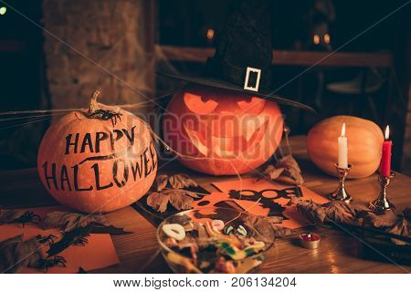 Close Up Of Cutted Pumpkin, Fall Leaves, Spider Web Net, Skull, Cap Of Witch, Bowl With Candies On T