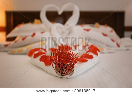 Bed decorated with flowers and towels in hotel room