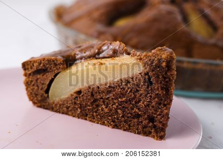 Slice of pear pie on pink plate with whole baked pie in background