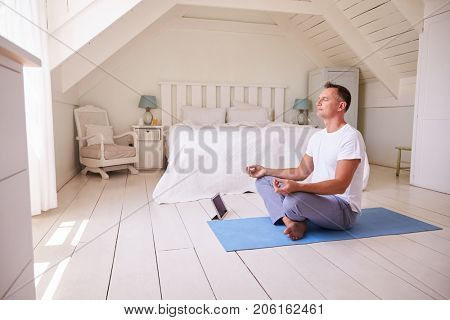 Mature Man With Digital Tablet Using Meditation App In Bedroom